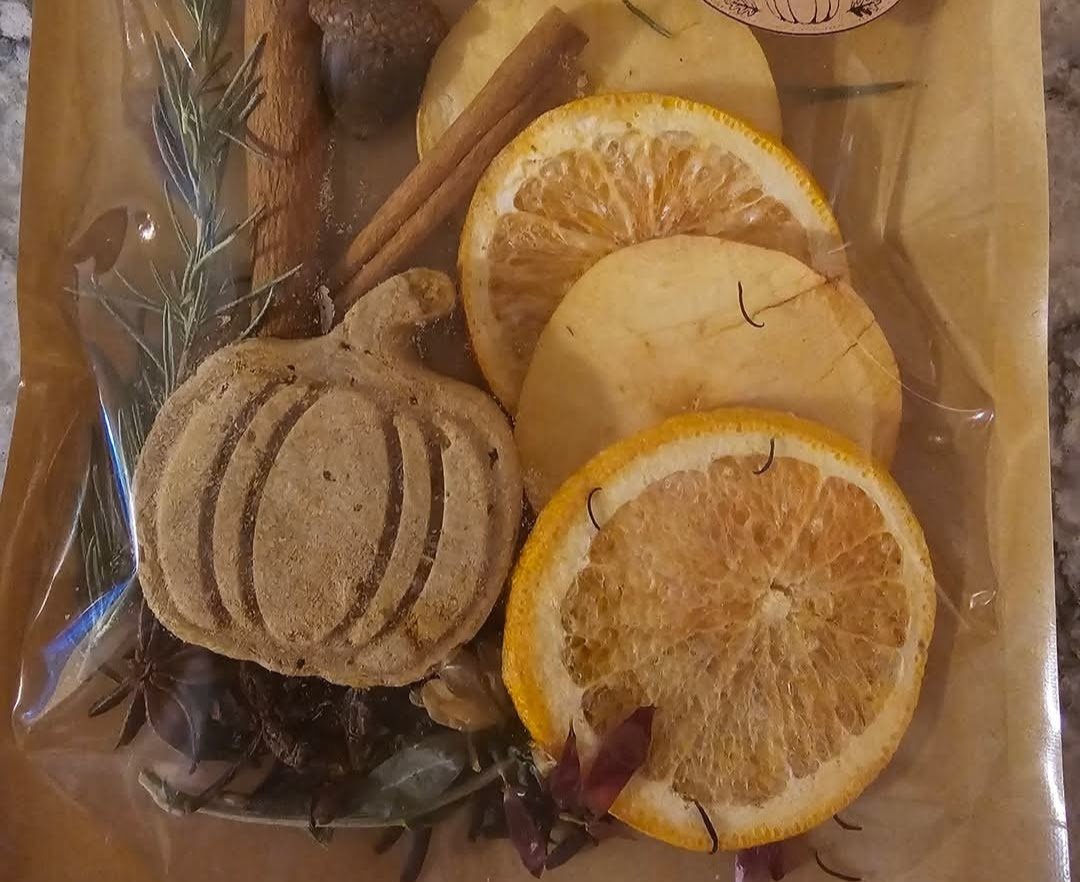 A simmer pot kit with dried orange slices, cinnamon sticks, rosemary and a pumpkin-shaped spice cake